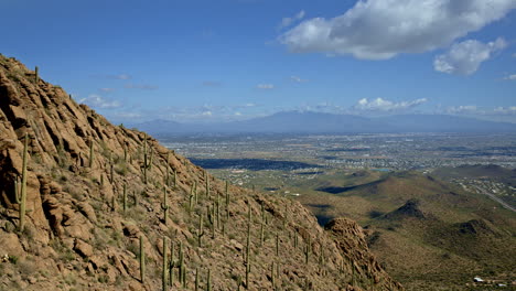 drone shot of cacti covered mountain with tucson arizona in the distance with mt lemmon in view