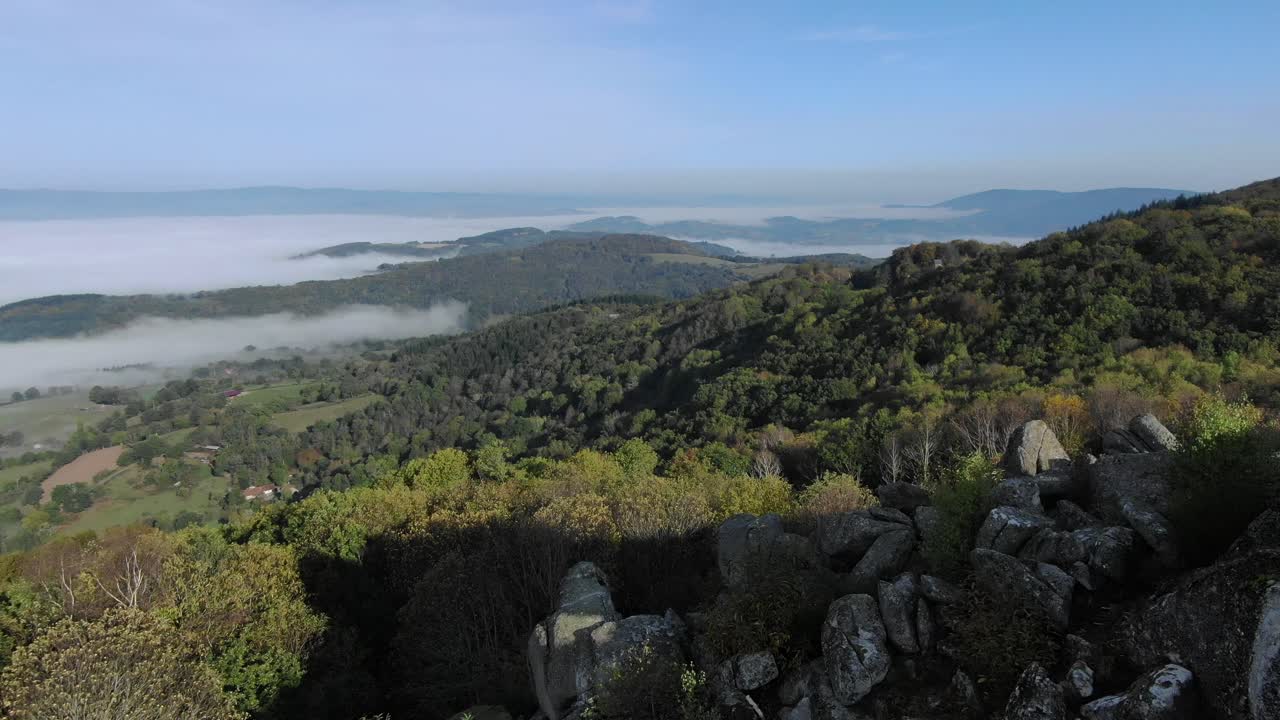 drone volando sobre rocas de granito de uchon con valle envuelto en niebla en el fondo, morvan en francia