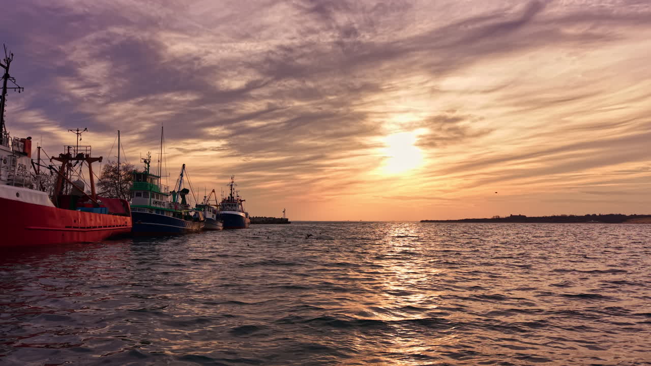 La serenità si rivela quando le barche attraccano al tramonto vicino al porto tranquillo, dipingendo il cielo con sfumature di arancione e lavanda
