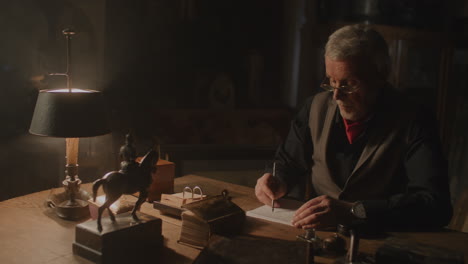 older passionate man evaluates an old watch in his office at night