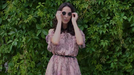 stylish hipster girl posing over green leaves bush background