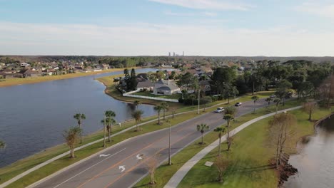 Aerial-flyover-beautiful-rural-suburban-city-of-Orlando-with-natural-lakes,-palm-trees-and-cars-driving-on-the-road