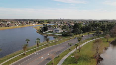 aerial flyover beautiful rural suburban city of orlando with natural lakes, palm trees and cars driving on the road