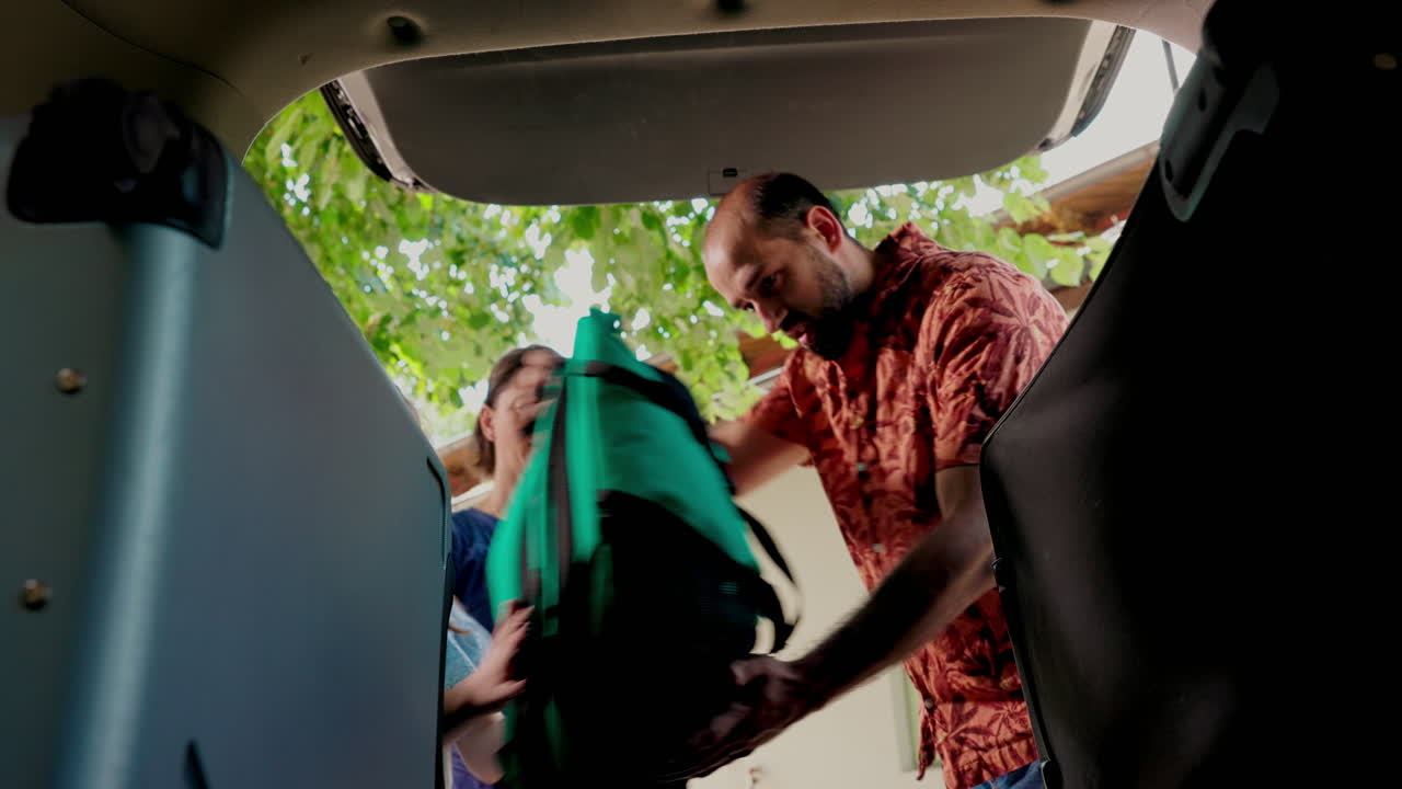 Family packing luggage in car trunk for travel