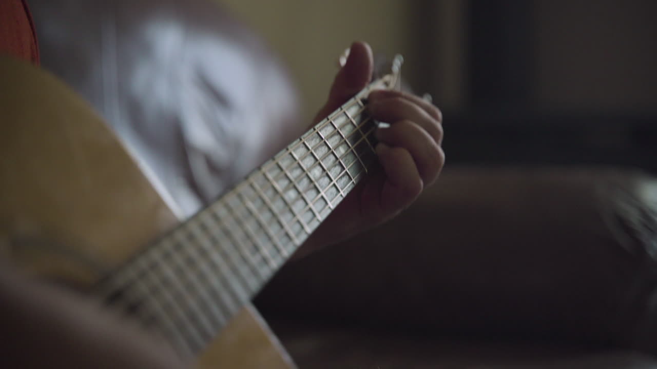 Close up of man's hands as he plays chords on an acoustic guitar