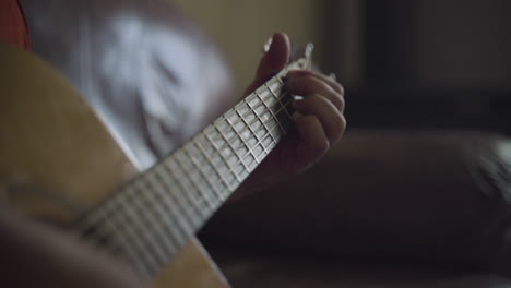 close up of man's hands as he plays chords on an acoustic guitar