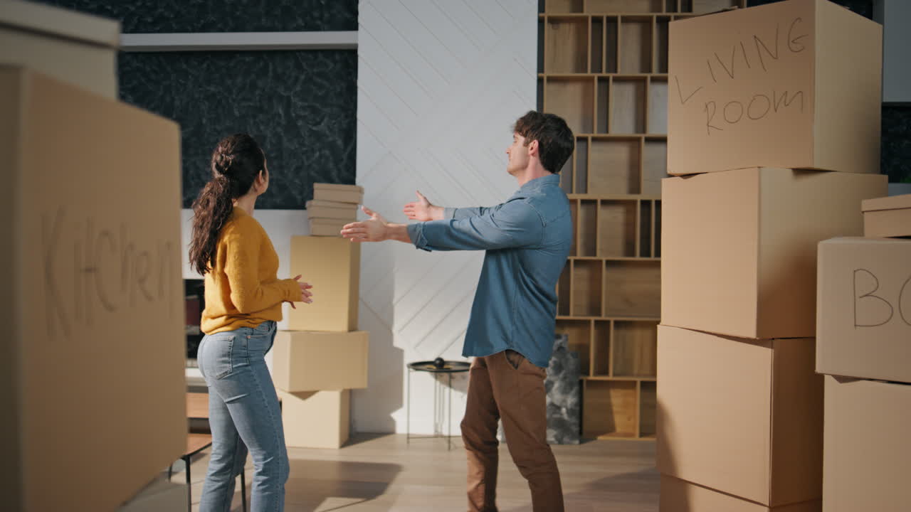 pareja feliz mudándose casa de pie sala de estar con cajas. cónyuges disfrutando de la casa