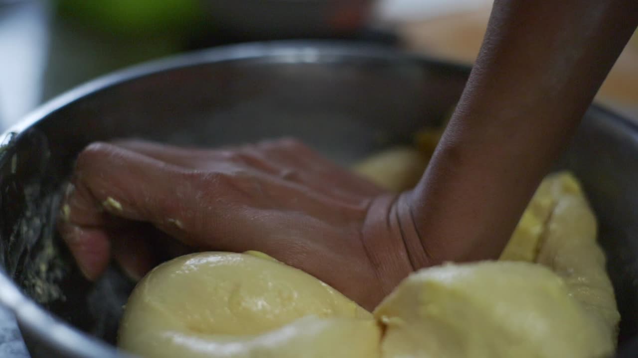 y la mezcla de masa húmeda y mantequilla siendo amassada a mano en un cuenco de acero, filmada en cámara lenta de primer plano