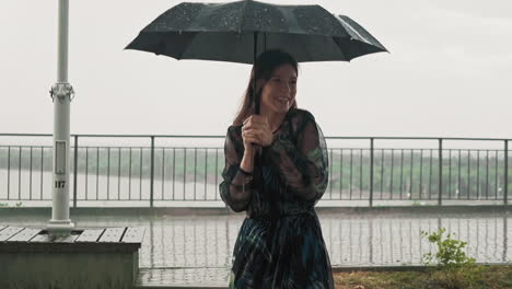 Joyful-lady-in-wet-dress-hides-under-black-umbrella-at-rain