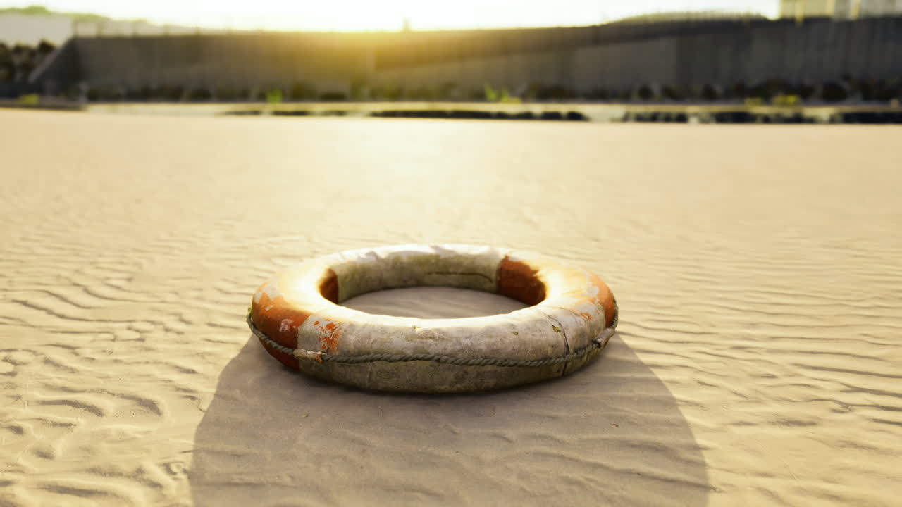 Lifebuoy resting on sandy shore at sunset with calm waters nearby