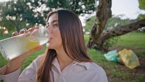 mujer de primer plano bebiendo una bebida en el parque. mujer feliz saciando la sed bebiendo
