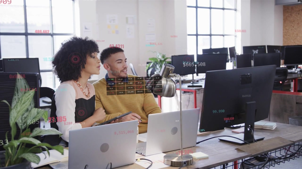 Two coworkers pointing at screen causing animated numbers, tapping tablet and analyzing sales data