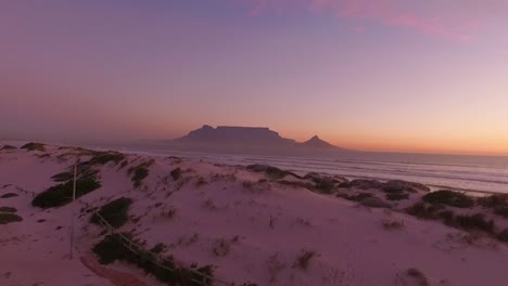 table mountain is seen at sunset from the coast of bloubergstrand in cape town south africa