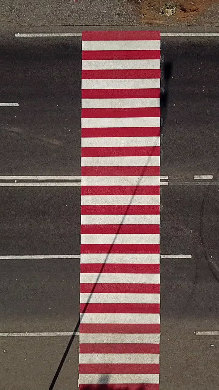 trucks are driving on the highway with a pedestrian crossing in red and white colours. Aerial view Vertical video
