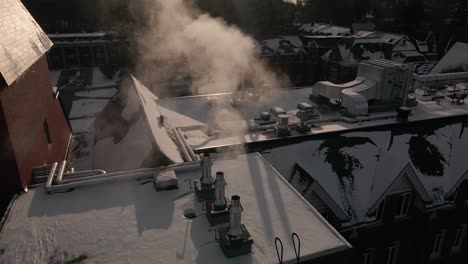 steams from chimney pipes on roof of bishop's university during cold season in lennoxville, sherbrooke, quebec canada