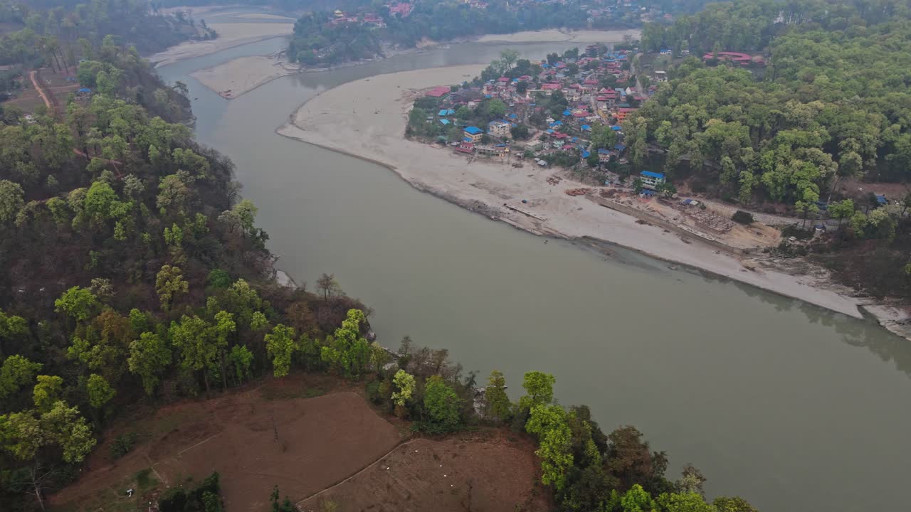 A breathtaking aerial view of a winding river passing through four remote villages surrounded by green mountains, showcasing rural harmony, nature, and the serene landscape beauty