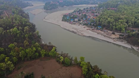 a breathtaking aerial view of a winding river passing through four remote villages surrounded by green mountains, showcasing rural harmony, nature, and the serene landscape beauty