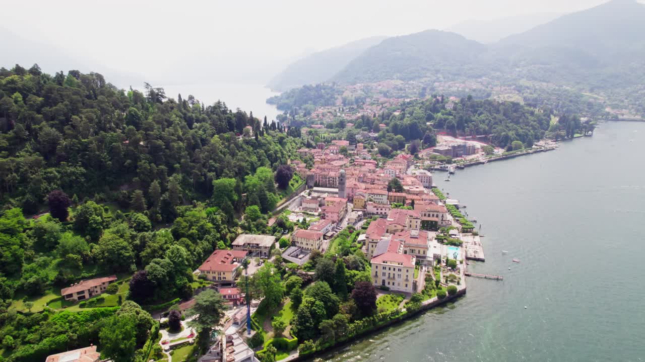 Filmagem aérea cinematográfica com drone movendo-se lateralmente para a direita, capturando a cidade de Bellagio no Lago de Como, Itália, com montanhas alpinas no plano de fundo