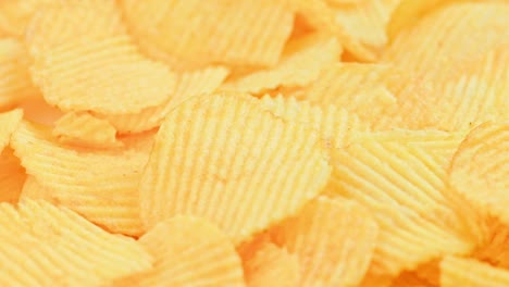 chips de patata de color amarillo ondulado en bucle giratorio en primer plano de fondo de cuadro completo
