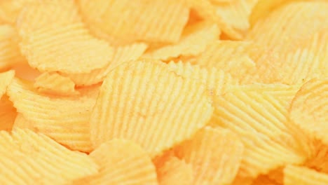 looped spinning yellow wavy potato chips full frame close-up background