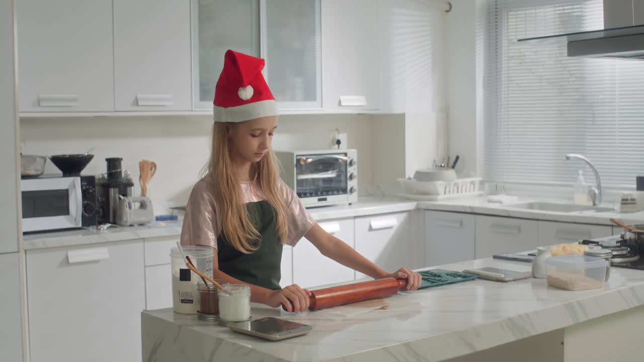Caucasian Girl in Christmas Hat Rolling Dough for Cookies
