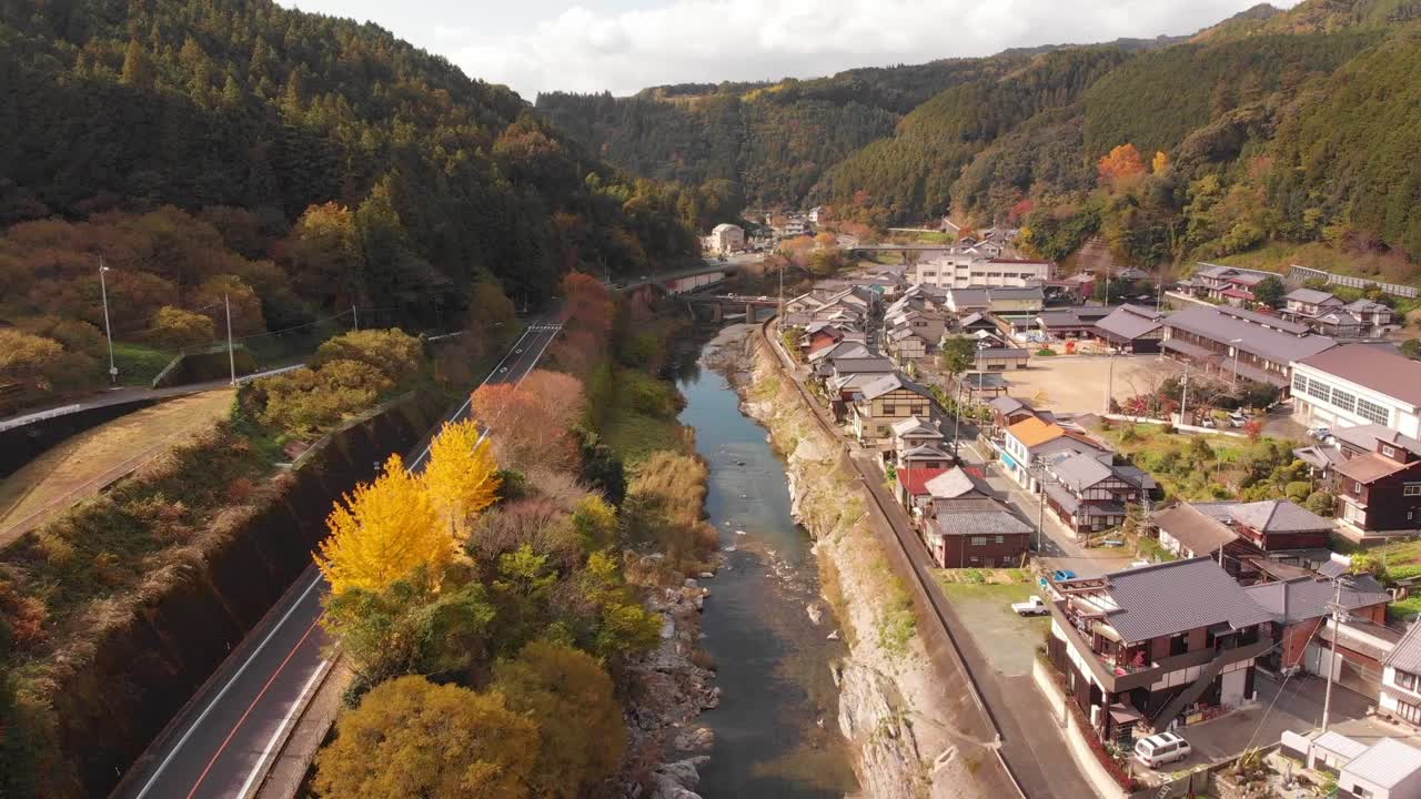 pequeño pueblo en las montañas con un río que atraviesa en otoño