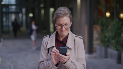 retrato amigable mujer caucásica de mediana edad sonriendo feliz disfrutando del uso del teléfono inteligente en la ciudad navegando por mensajes enviando mensajes de texto en el teléfono móvil usando gafas en cámara lenta