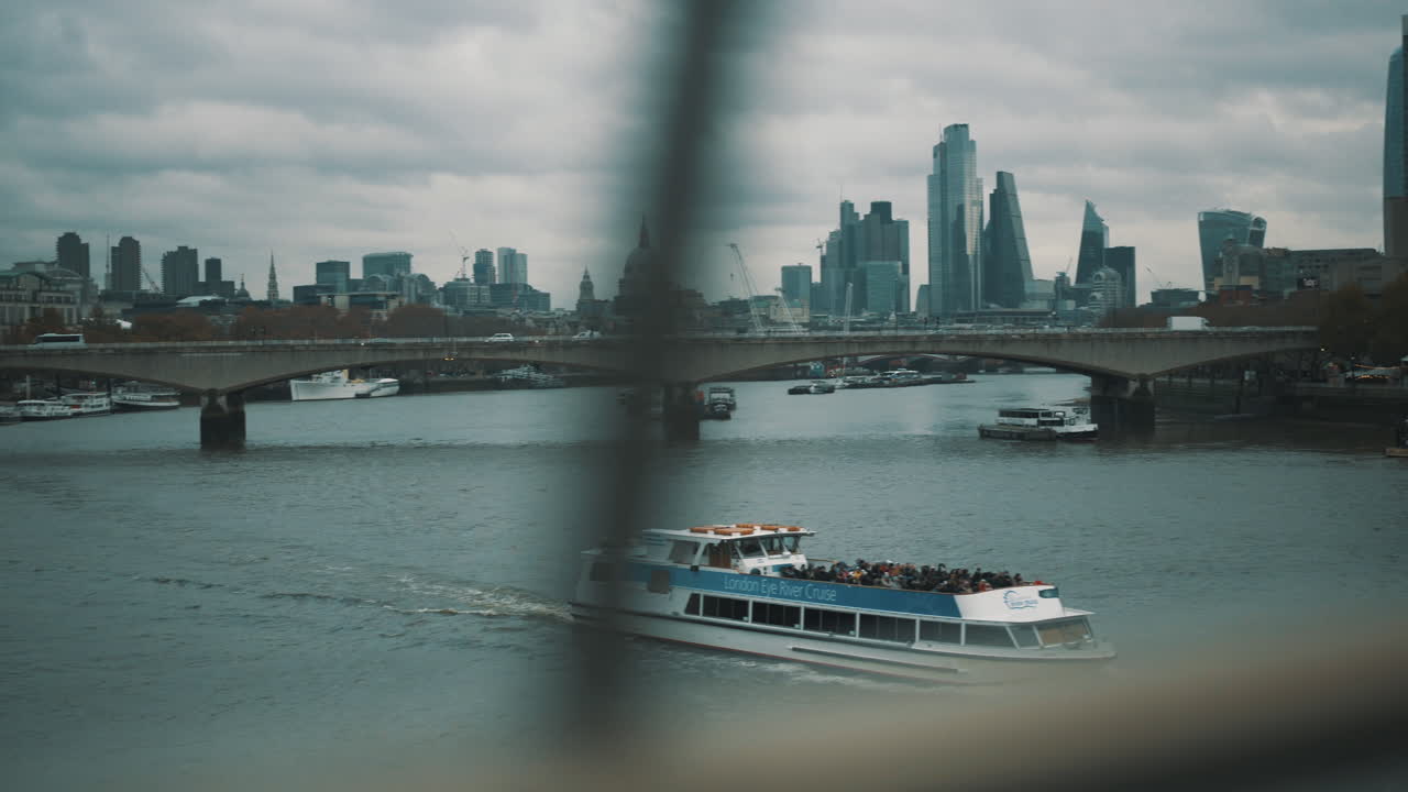 London scene ferry boat travels in River Thames with Waterloo Bridge and city skyline in background