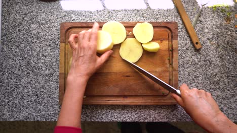 toma aérea de cortar patatas frescas descascaradas con un cuchillo de cocina