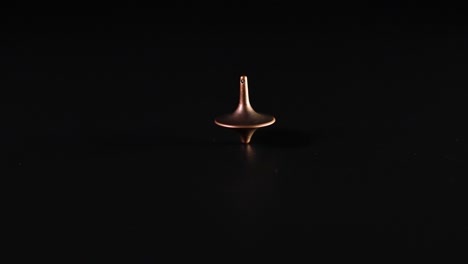 a spinning top rotating on a dark surface