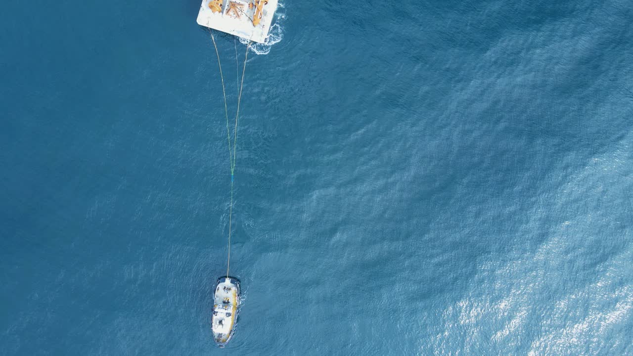 equipos de construcción en una barcaza flotante remolcada a través del océano por un remolcador