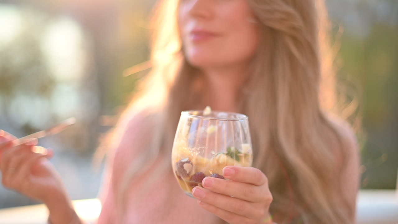Donna che mangia una macedonia con semi di chia in un parco al tramonto