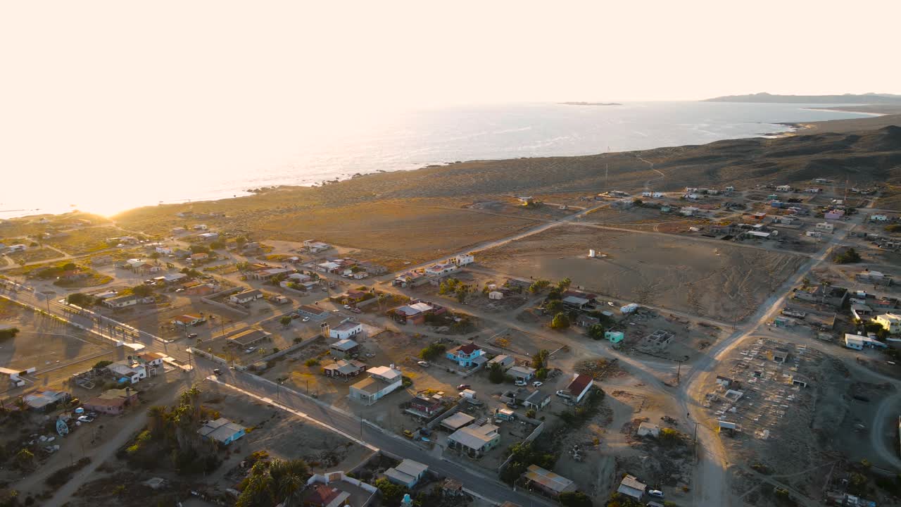 Panoramica su una città costiera desertica al tramonto con luce dorata che accarezza le case