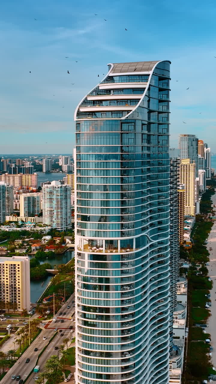 Volando intorno all'edificio alto con facciata in vetro che si erge nella fila di grattacieli a Miami Beach. Vista panoramica della costa dell'Oceano Atlantico.