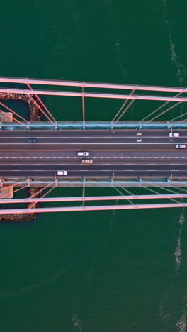 flyover huge impressive bridge with fast moving cars. bridge construction at the backdrop of sea-green river. vertical video