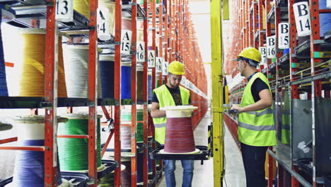 cable spool inside factory. warehouse worker checking stock of cables