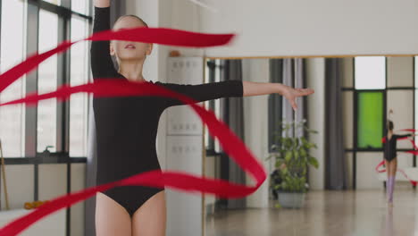 young girl practising rhythmic gymnastics with a ribbon in the gym 1