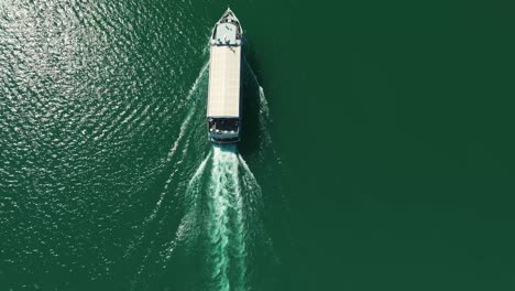 Eine-Drohne-Verfolgt-Ein-Boot,-Das-Sanft-über-Die-Smaragdgrüne-Fläche-Des-Wolfgangsees-Fährt