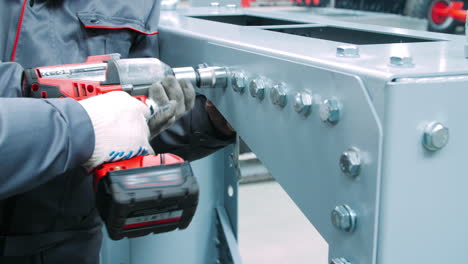 tightening bolts on metal surface of industrial machine. using screwdriver