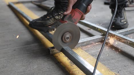 the man works near the circular saw. flames fly from the hot metal. the man worked on the steel.