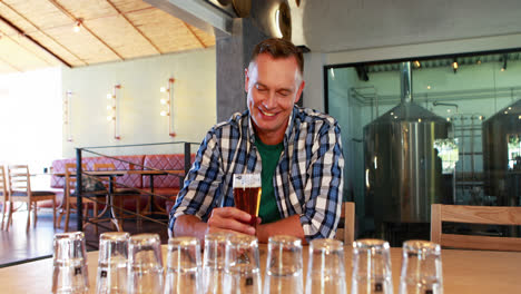 Smiling-man-having-glass-of-beer-at-counter-4k
