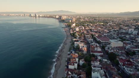 Drone-video-capturing-the-coast-of-Puerto-Vallarta-from-a-great-height,-featuring-the-hotel-zone-and-the-sea,-showcasing-the-vast-size-of-Banderas-Bay