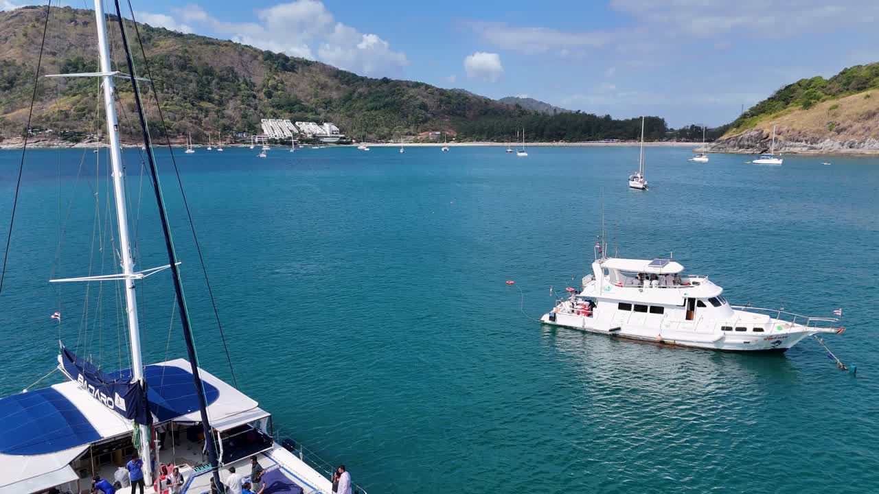 los catamaranes se deslizan a través de las aguas turquesas de phuket bajo un cielo despejado, capturando una escena tropical tranquila con un suave movimiento de la cámara.