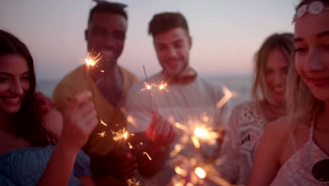 young multi-ethnic hipster friends celebrating with sparklers at rooftop party