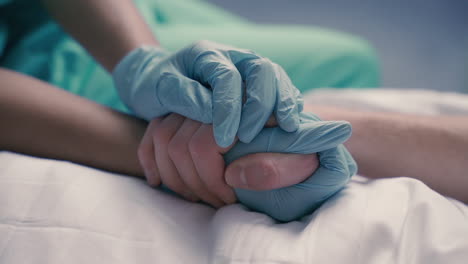 détail des mains d'une infirmière saisissant et réconfortant les mains d'un patient malade sur un lit d'hôpital 1