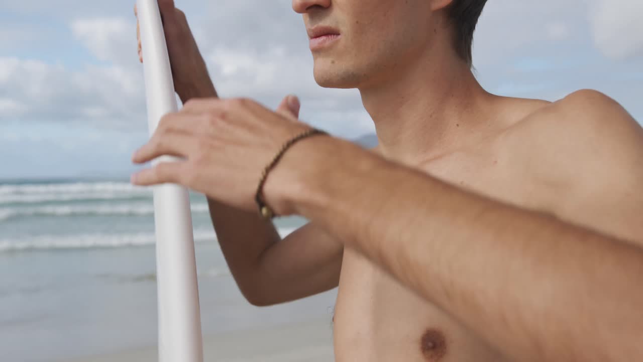 Giovane uomo in spiaggia con tavola da surf