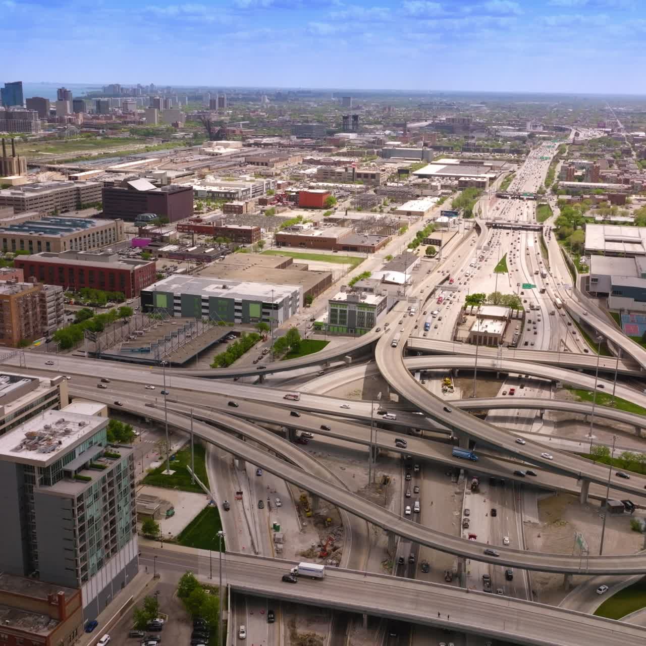 Road loops and junctions with multiple automobiles moving along. Low architecture of Chicago city. Aerial view