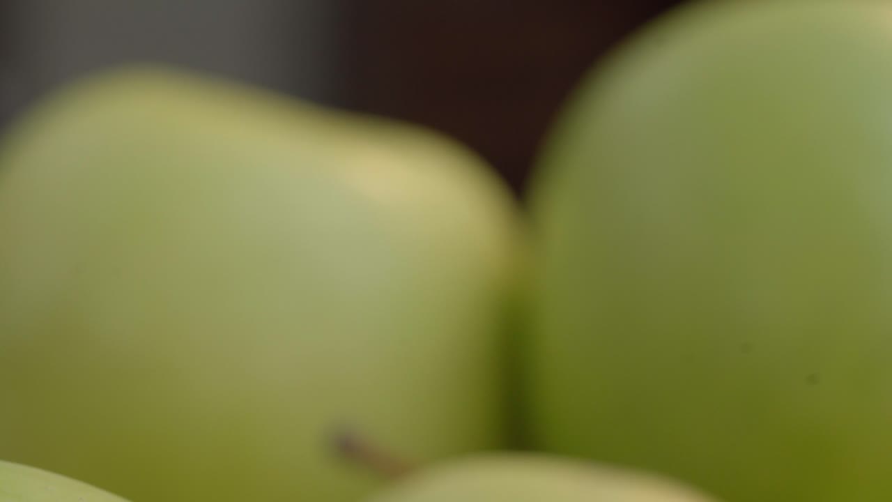 Detailed close-up shot of fresh green apples showcasing their smooth texture and vibrant color. Perfect for illustrating freshness and natural produce in bright, natural lighting