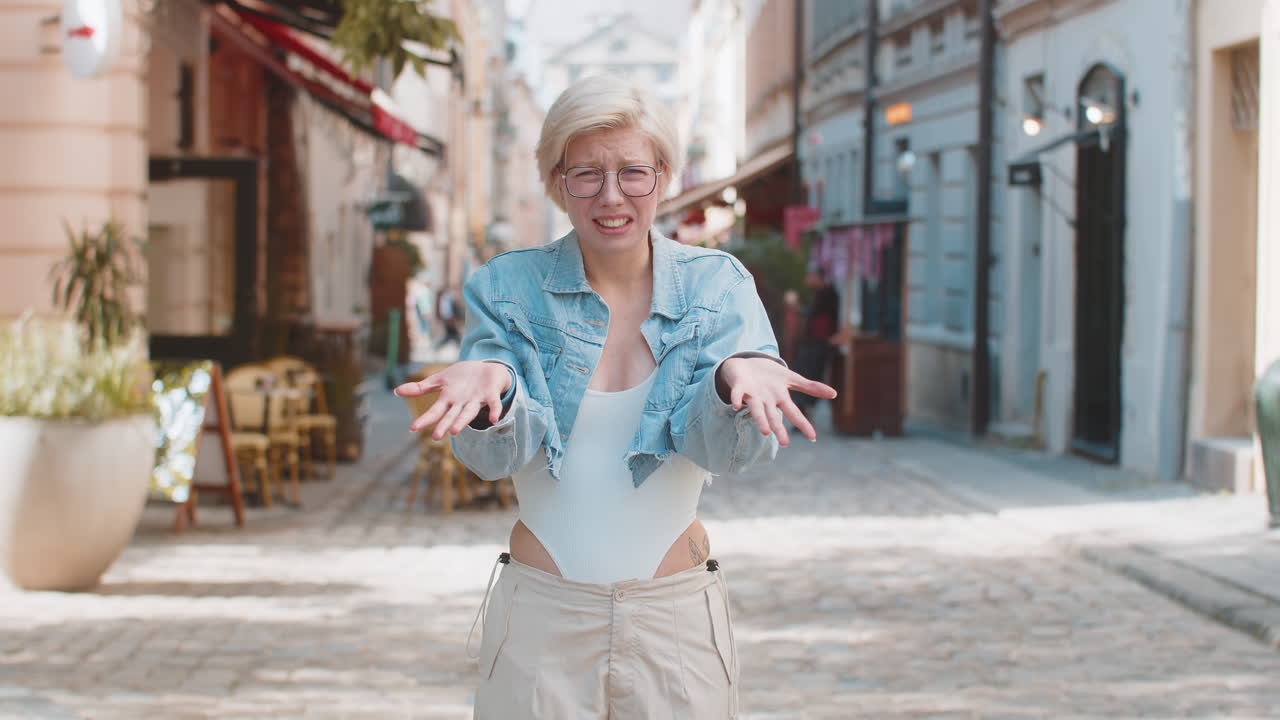 Doubtful sad frustrated young caucasian woman shrugging shoulders dont know answer on city street