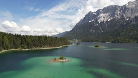 vista aérea del colorido lago eibsee en baviera, alemania, rodeado de pinos y una lejana cordillera montañosa, capturando la esencia de la armonía y la serenidad de la naturaleza.